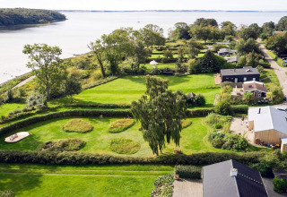 Luchtbeeld van een vakantiehuis in Rønde, Denemarken, met groene tuinen en zicht op het water.