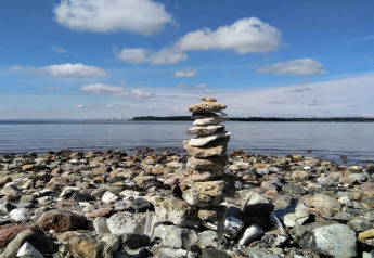 Cairn de pierres sur plage rocheuse sous ciel bleu près d'une maison 4 étoiles à Rønde, Danemark.