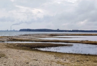 Strand- und Meeresblick beim 4-Sterne-Ferienhaus in Rønde, Dänemark, mit Fabrikrauch am Horizont.