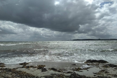 Vista sul mare e sulla spiaggia sotto nuvole drammatiche, scattata da una casa vacanze a Rønde, Danimarca.