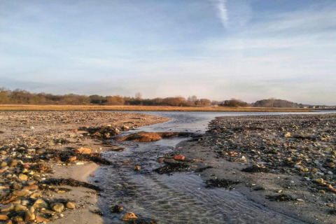 Blick von einem 4-Sterne-Ferienhaus in Rønde, Dänemark auf die Küste mit Bach und Kieselsteinen.