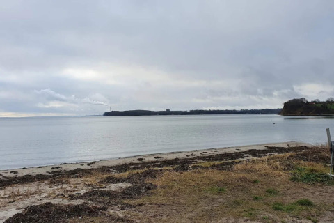 Blick auf ruhigen Strand und Meer unter grauem Himmel bei ‘4 star holiday home in Rønde’, Dänemark.