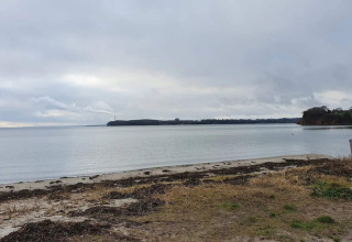 View of a peaceful beach and calm sea under a cloudy sky at ‘4 star holiday home in Rønde’, Denmark.