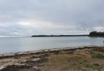 Udsigt over rolig strand og hav med grå himmel ved ferieboligen ‘4 star holiday home in Rønde’, Danmark.