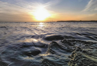 Sunset over the sea taken at "4 star holiday home in Rønde" in Denmark, gentle waves in the foreground.