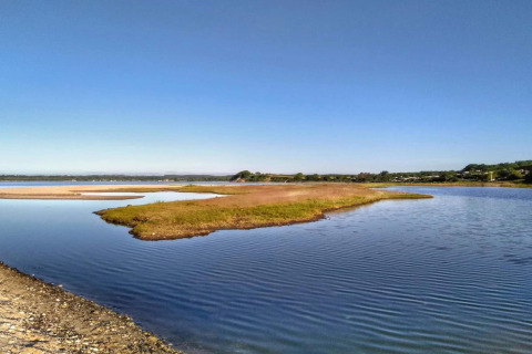 Vista di un lago calmo con piccole isole erbose sotto un cielo azzurro vicino a una casa vacanze a Rønde.