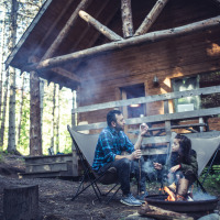 Vader en dochter bij kampvuur voor hun cabin
