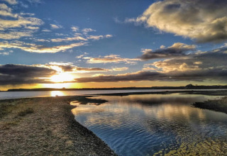 Sonnenuntergang über dem Wasser bei der „4 star holiday home in Rønde“ Lodge in Dänemark mit Wolkenhimmel.