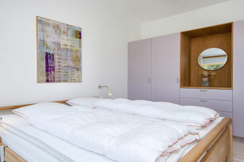 Chambre dans une maison de vacances 4 étoiles à Rønde, Danemark, avec lit double, placard et tableau.