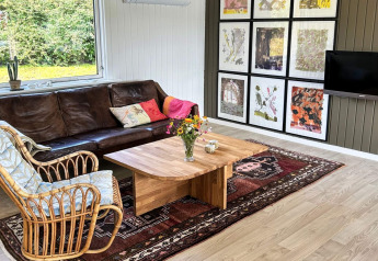 Woonkamer in een 4-sterren vakantiehuis in Rønde, Denemarken, met lederen zetel en wandkunst.