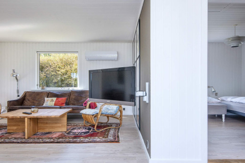 Salón moderno con sofá marrón, mesa de centro, TV y vista al dormitorio en casa vacacional en Rønde, Dinamarca.