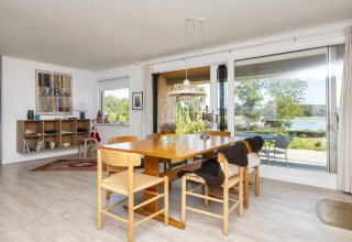 Sala da pranzo in casa vacanza 4 stelle a Rønde, Danimarca, con ampie finestre e vista sul lago.