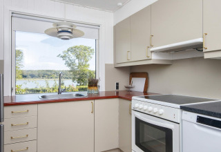 Moderne keuken met groot raam en uitzicht op meer en bos in 4-sterren vakantiehuis in Rønde, Denemarken.