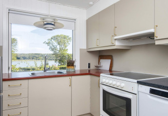 Moderne keuken met groot raam en uitzicht op meer en bos in 4-sterren vakantiehuis in Rønde, Denemarken.