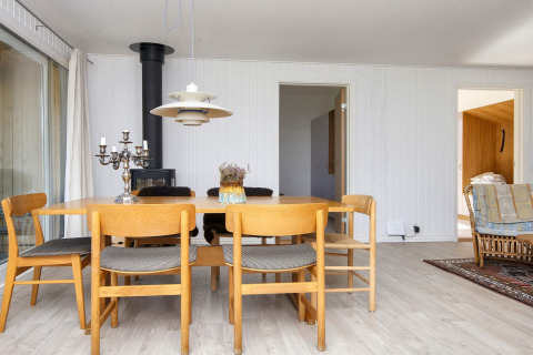 Salle à manger dans une maison de vacances à Rønde, Danemark, avec table en bois et poêle.