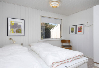 Slaapkamer met twee eenpersoonsbedden, witte muren, moderne kunst en stoel in Rønde, Denemarken.