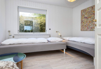 Soveværelse med to enkeltsenge, stort vindue, væglamper og moderne kunst på væggen i Rønde.