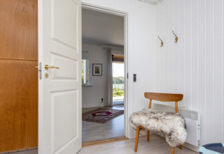 Entrada de casa vacacional 4 estrellas en Rønde, Dinamarca, con banco y puertas abiertas al salón.
