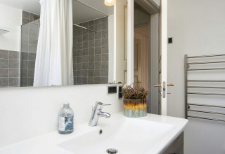 Baño moderno en casa de vacaciones 4 estrellas en Rønde, Dinamarca, con lavabo, espejo y toallero.