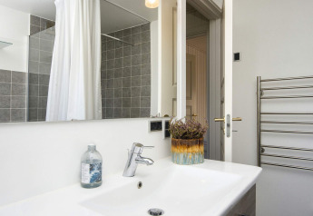 Moderne badkamer in 4-sterren vakantiewoning in Rønde met wastafel, spiegel en handdoekradiator.