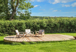 Wooden deck with three chairs and a table at a 4-star holiday home in Rønde, Denmark, on a sunny day.