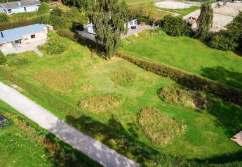 Luchtfoto van het viersterren vakantiehuis in Rønde, Denemarken, met tuin, grasveld en paardenwei.