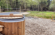 Houten hot tub en volleybalveld in de natuur bij 5-sterren vakantiewoning in Øster Assels, Denemarken.