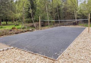 Pista de bádminton exterior con suelo de asfalto junto a un bosque en casa de vacaciones de 5 estrellas en Øster Assels, Dinamarca.