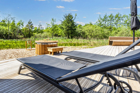 Buitenterras met ligstoelen, hot tub en houten bank bij 5-sterren vakantiehuis in Øster Assels, Denemarken