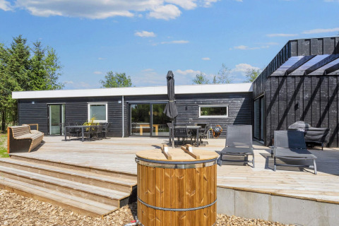 Terraza de la casa de vacaciones de 5 estrellas en Øster Assels, Dinamarca, con muebles y jacuzzi exterior.