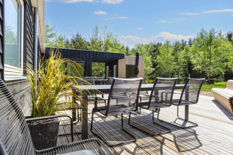 Buitenterras met tafel en stoelen aan 5-sterren verblijf in Øster Assels, midden in het groen.