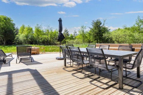 Ruim terras met moderne tuinmeubelen, ligstoelen en parasol aan het groen in Øster Assels, Denemarken.