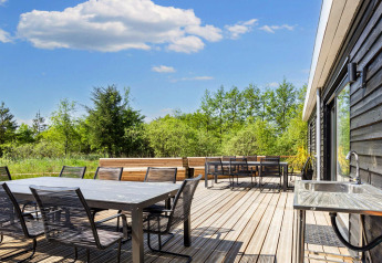Udendørs terrasse ved 5 stjernet feriehus i Øster Assels, Danmark, med spiseområde og grøn udsigt.