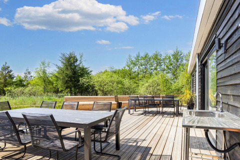 Ampia terrazza nella casa vacanze a 5 stelle di Øster Assels, Danimarca, con area pranzo e vista verde.
