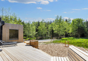 Outdoor terrace with modern wooden lodge, hot tub, forest view at 5 star holiday home in Øster Assels, Denmark.