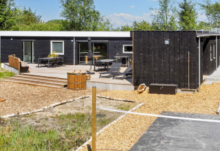 Modern vakantiehuis in Øster Assels, Denemarken, met houten terras, buitenzitjes en groene omgeving.