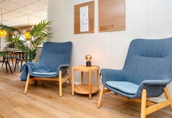 Modern lounge area in a 5 star holiday home in Øster Assels, Denmark, featuring blue chairs and a lamp.