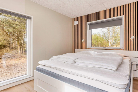 Slaapkamer in een 5-sterren vakantiehuis in Øster Assels, Denemarken, met een ruim bed en houten wand.