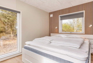 Slaapkamer in 5-sterren vakantiehuis in Øster Assels, Denemarken, met groot bed en houten wandpanelen.