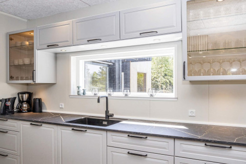 Cocina moderna en '5 star holiday home in Øster Assels', Dinamarca, con encimera negra y ventana.
