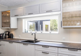 Cocina moderna en '5 star holiday home in Øster Assels', Dinamarca, con encimera negra y ventana.