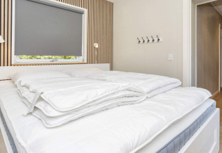 Moderne slaapkamer met groot bed en witte dekens in een 5-sterren vakantiewoning in Øster Assels, Denemarken.