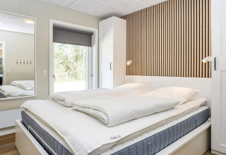 Camera moderna con parete a doghe, letto matrimoniale e grande specchio in casa vacanze 5 stelle a Øster Assels.