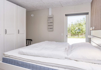Lichte slaapkamer met dubbel bed, kasten en buitenzicht in vijfsterren vakantiewoning in Øster Assels.