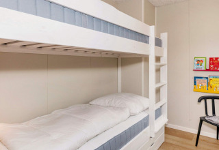 Lichte kinderkamer met stapelbed, boekenrekken en stoel in het 5-sterren vakantiehuis te Øster Assels.