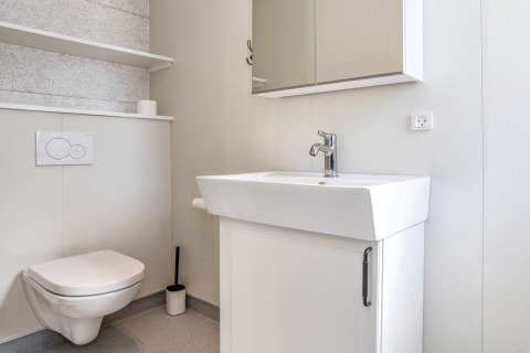 Modernes Badezimmer mit wandhängender Toilette, weißem Waschbecken und Spiegelschrank in Dänemark.