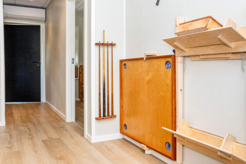 Couloir d'une location de vacances avec une table de billard pliante et des queues accrochées au mur à Øster Assels.