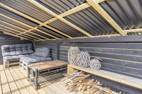 Espace lounge sur terrasse avec canapés, lanternes et bois, dans une maison de vacances 4 étoiles à Løgstør.