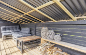 Overdekte zithoek met sofa, lantaarns en hout in een 4-sterren vakantiehuis in Løgstør, Denemarken.