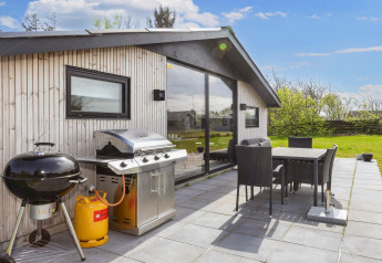 Terrasse extérieure d’une maison de vacances à Løgstør, Danemark, avec barbecue, table et chaises de jardin.